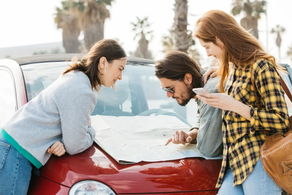 Three people inspecting car damage after an accident on a city street