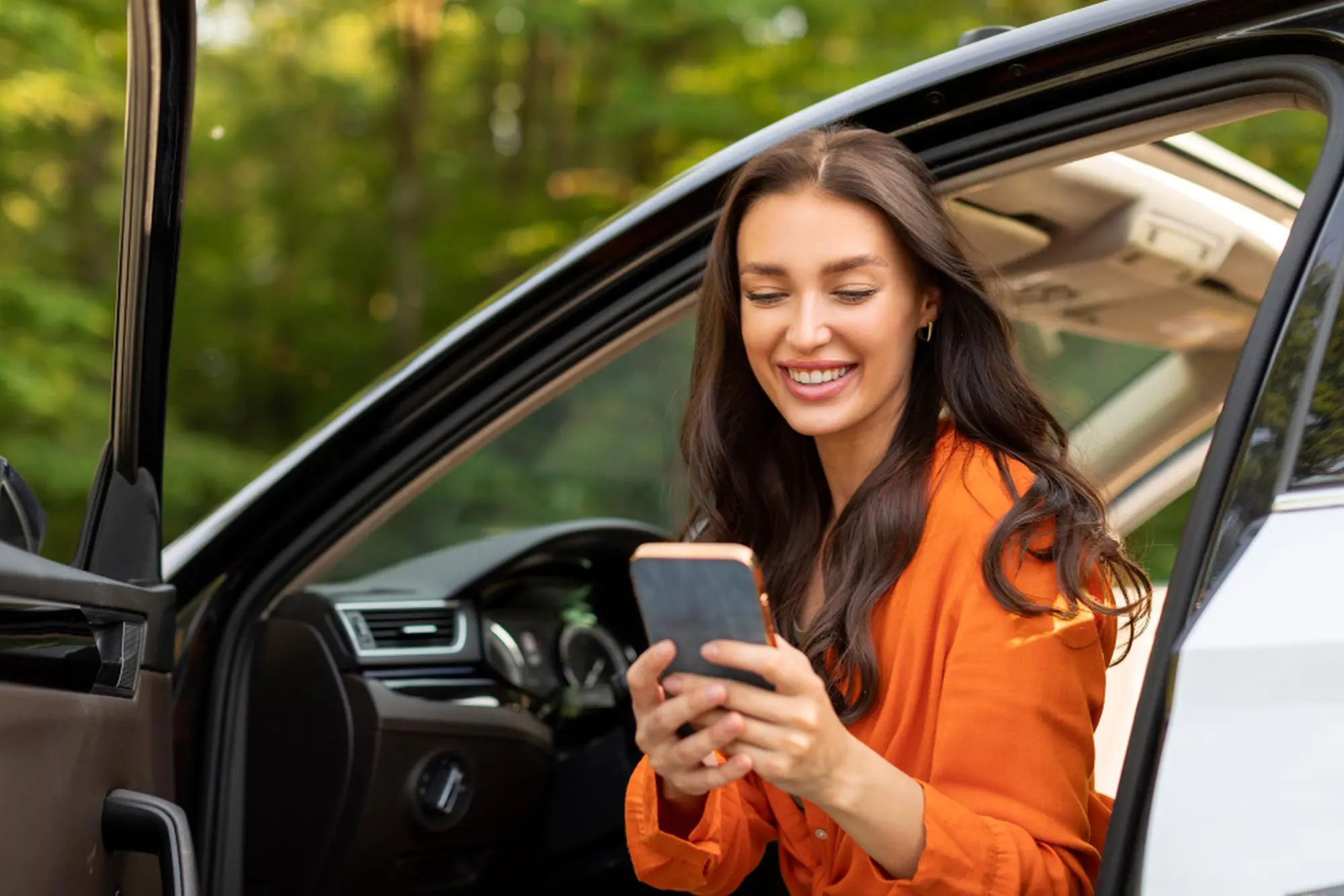 Smiling person with phone in a car.